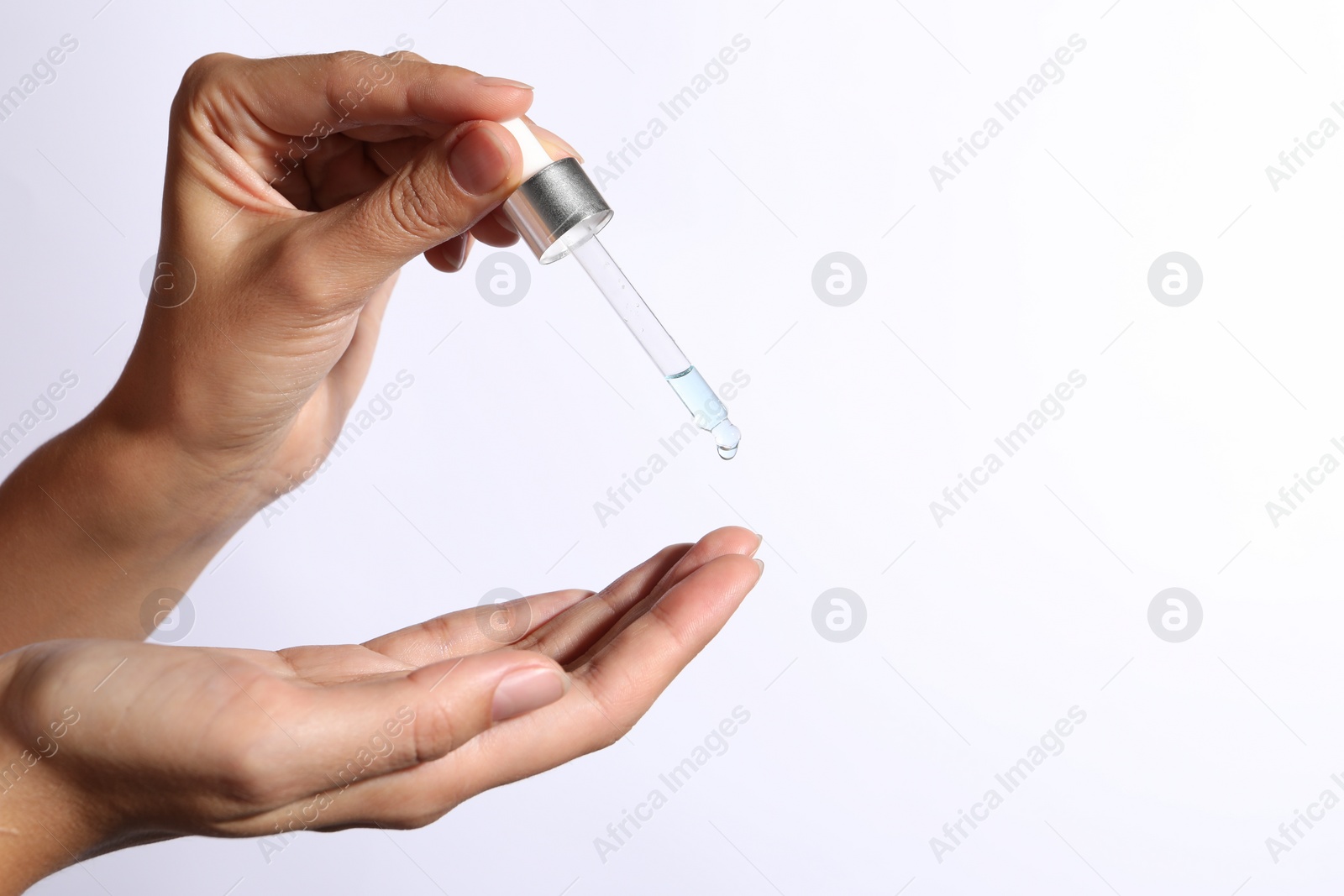 Photo of Woman applying cosmetic serum onto her finger on white background, closeup. Space for text