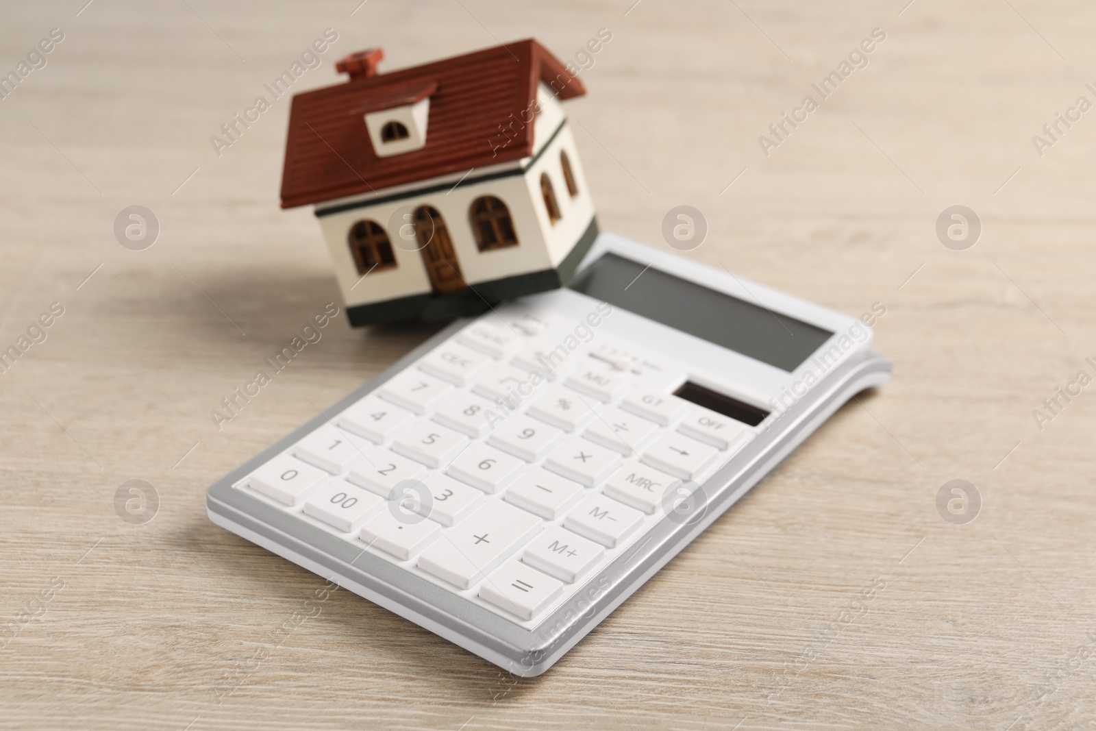 Photo of Mortgage concept. House model and calculator on wooden table, closeup