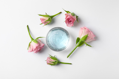 Composition with cosmetic gel and beautiful flowers on white background, top view