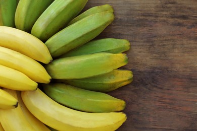 Bunches of tasty bananas on wooden table, flat lay. Space for text