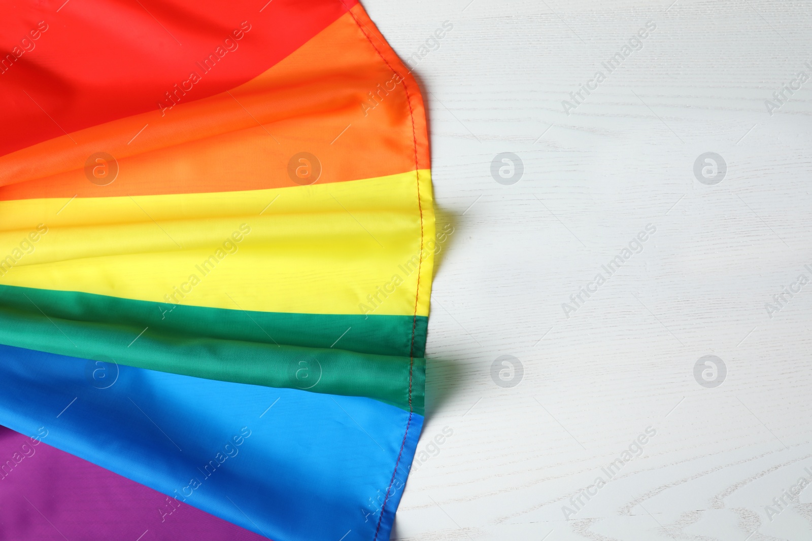 Photo of Rainbow gay flag on wooden background, top view with space for text. LGBT concept