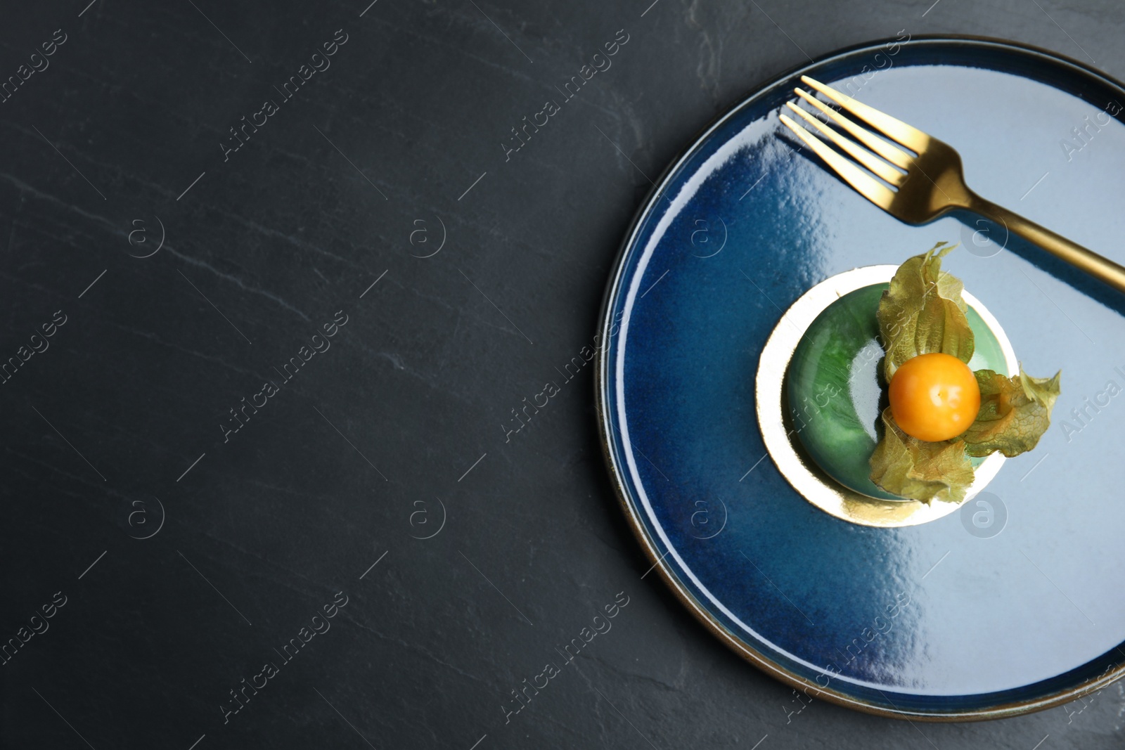 Photo of Delicious dessert decorated with physalis fruit on black table, top view. Space for text