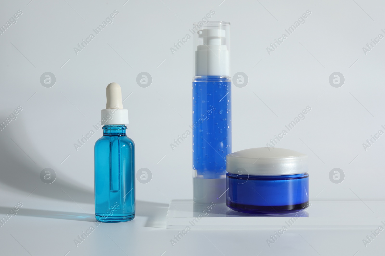 Photo of Different containers with cosmetic products on light background