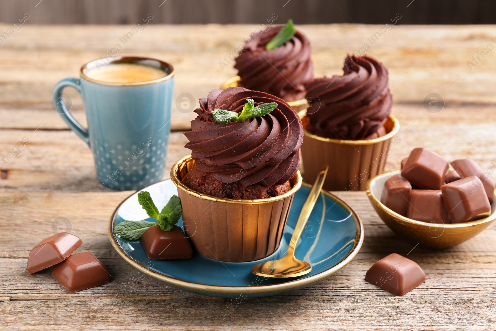 Photo of Delicious cupcakes with mint and chocolate pieces on wooden table