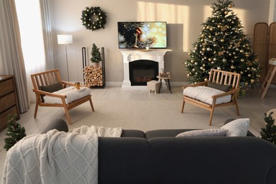 Photo of Modern TV set on light wall in room decorated for Christmas