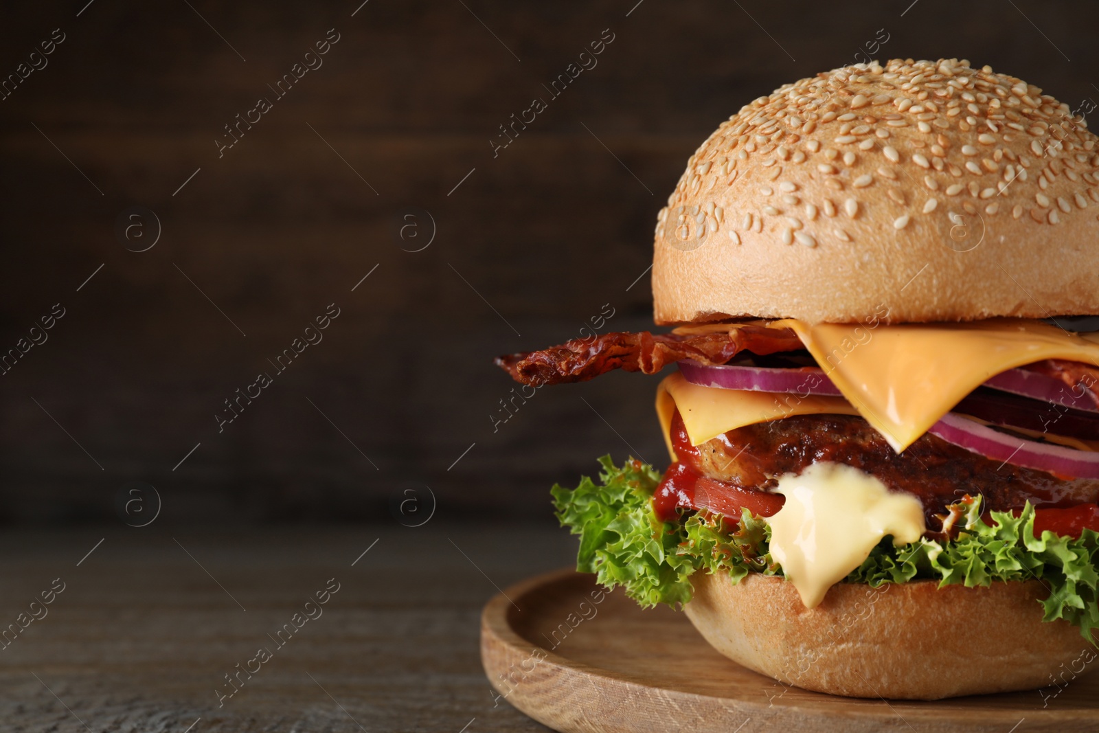 Photo of Plate with juicy bacon burger on wooden table. Space for text