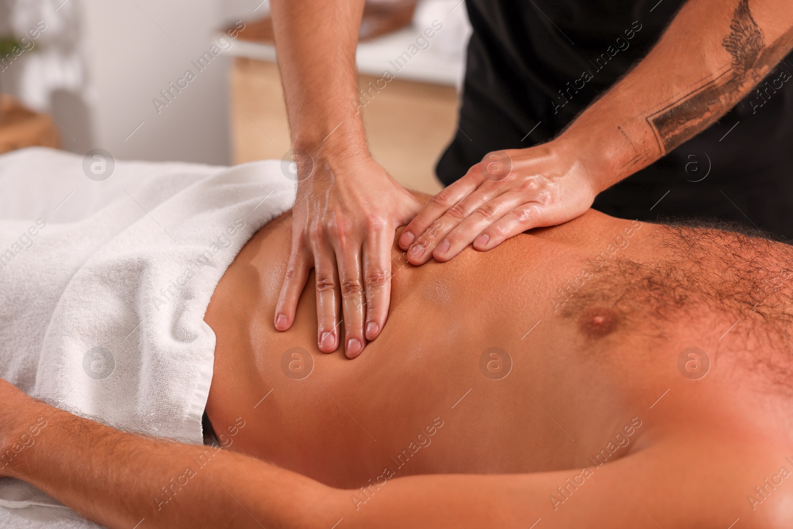 Photo of Man receiving professional belly massage in spa salon, closeup