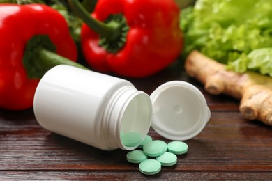 Photo of Dietary supplements. Overturned bottle, pills and food products on wooden table, closeup