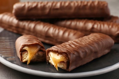 Photo of Sweet tasty chocolate bars with caramel on plate, closeup