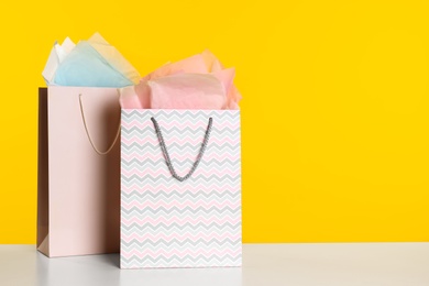 Photo of Shopping bags with paper on yellow background. Space for text