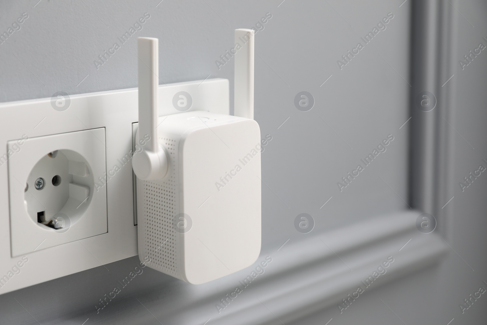 Photo of Wireless Wi-Fi repeater on light grey wall, space for text