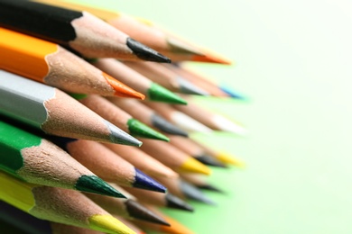 Photo of Color pencils on green background, closeup. Space for text