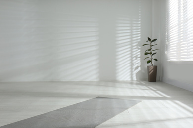 Photo of Unrolled grey yoga mat on floor in room. Space for text