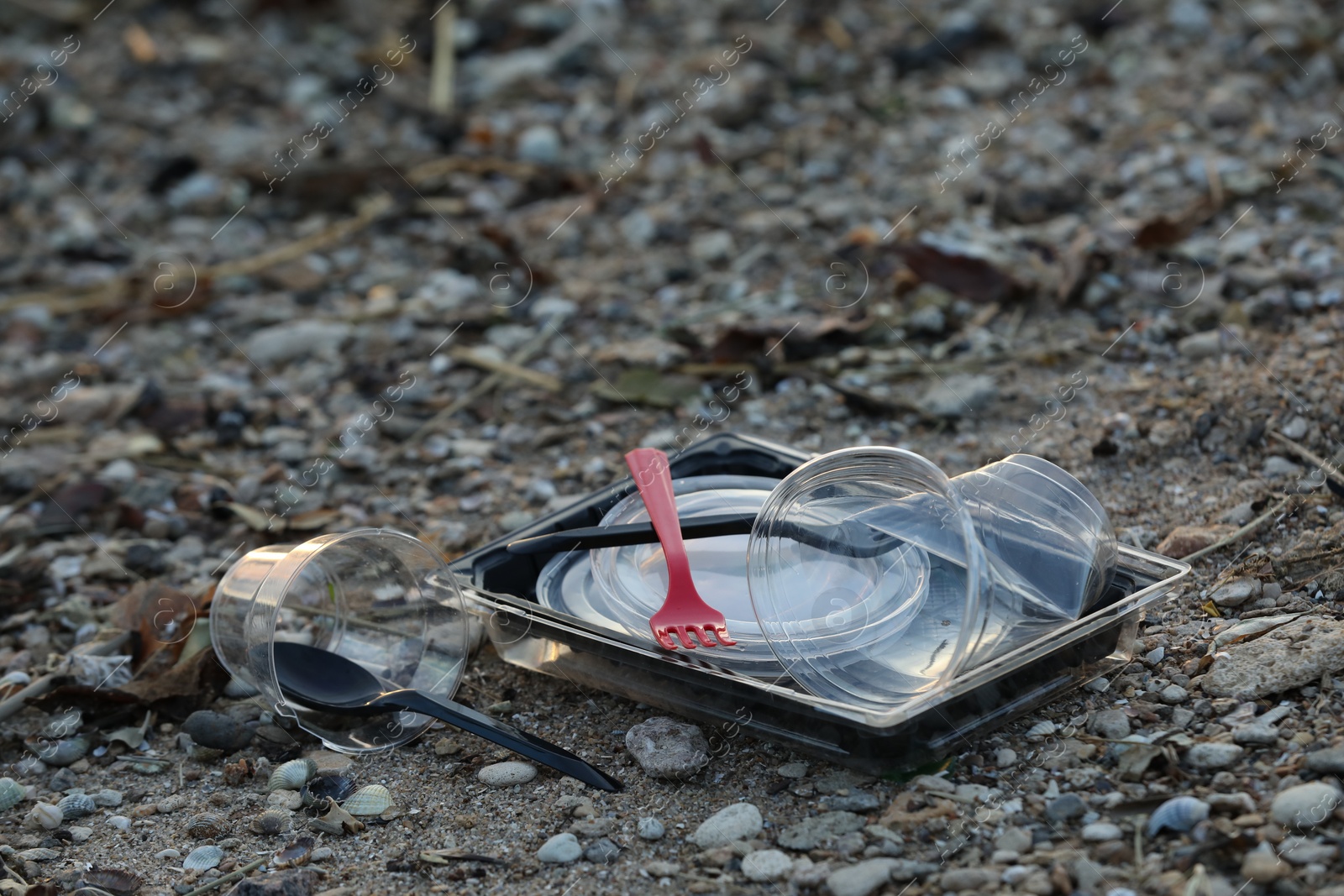 Photo of Used plastic tableware at beach, space for text. Environmental pollution concept