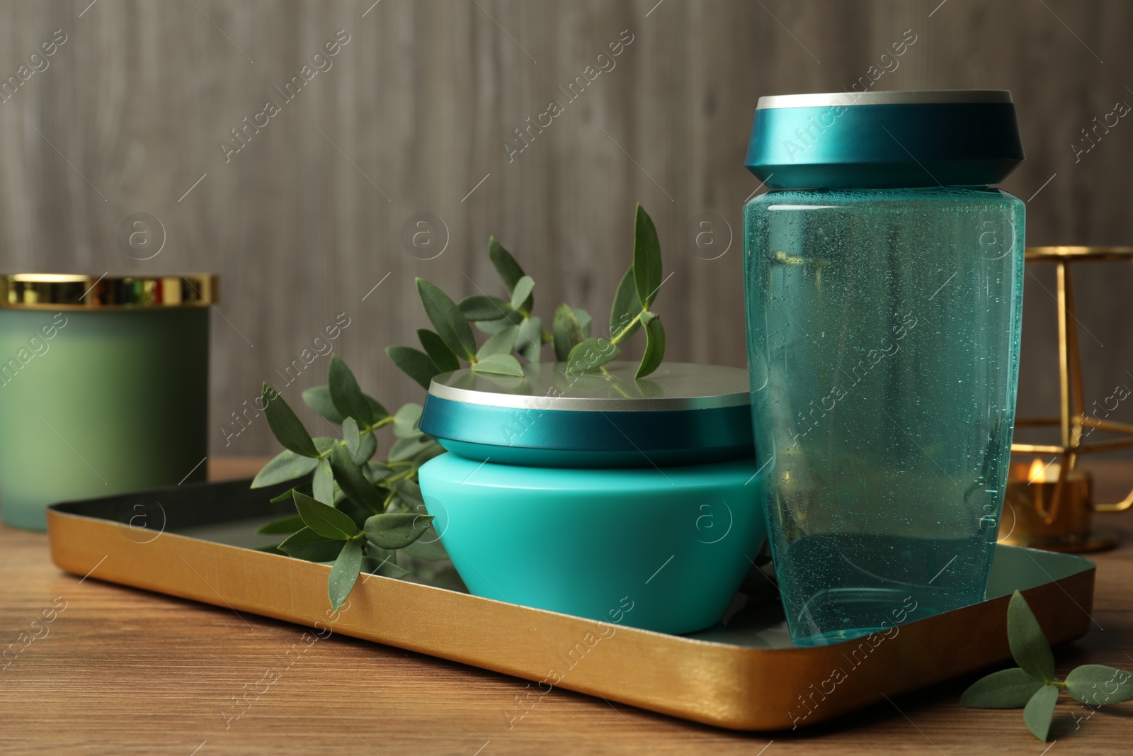 Photo of Hair care cosmetic products and green leaves on wooden table