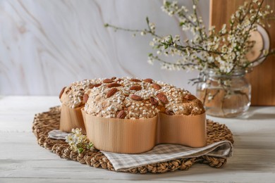 Photo of Delicious Italian Easter dove cake (Colomba di Pasqua) and flowers on white wooden table