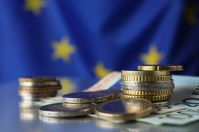 Photo of Coins and banknotes on table against European Union flag, closeup. Space for text