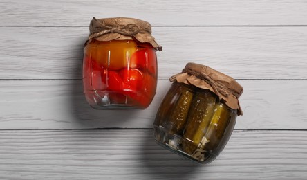Photo of Jars with pickled vegetables on white wooden table, flat lay