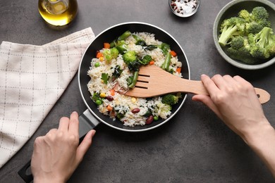 Photo of Woman taking tasty fried rice with vegetables at black table, top view