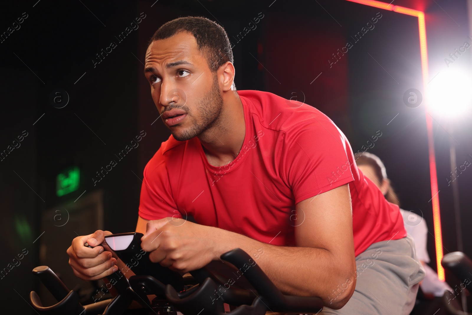 Photo of Young man training on exercise bike in fitness club