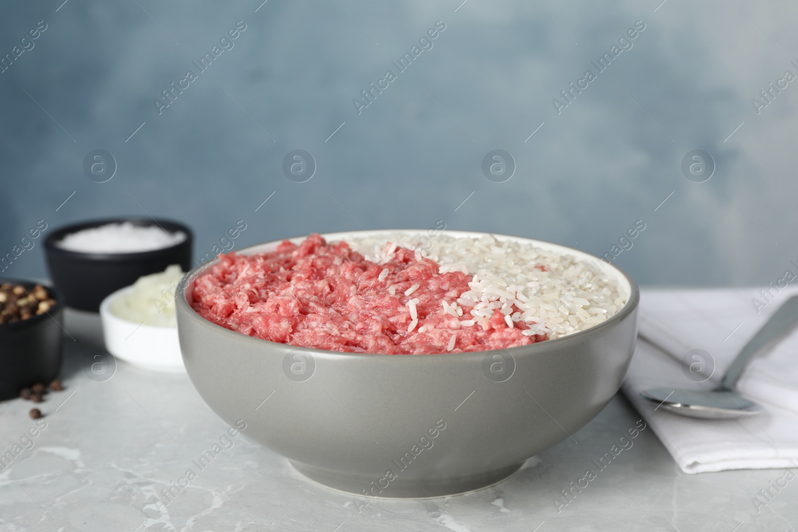 Photo of Minced meat with rice in bowl for stuffed cabbage rolls on light grey table