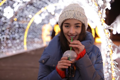 Woman with cup of mulled wine at winter fair. Space for text