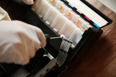 Photo of Repairman with screwdriver fixing modern printer, closeup