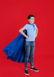 Photo of Teenage boy in superhero costume on red background