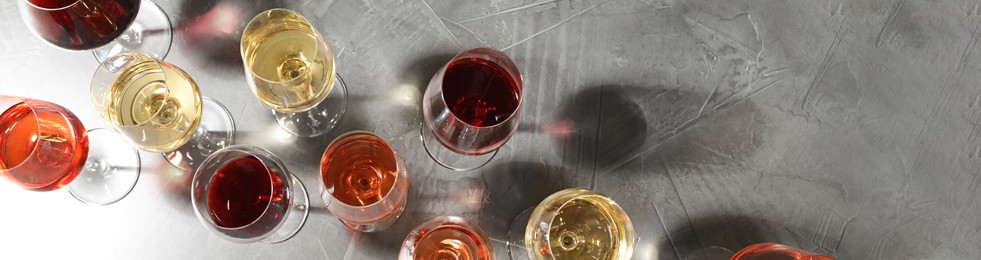 Image of Glasses with different wines on light grey table, flat lay. Banner design