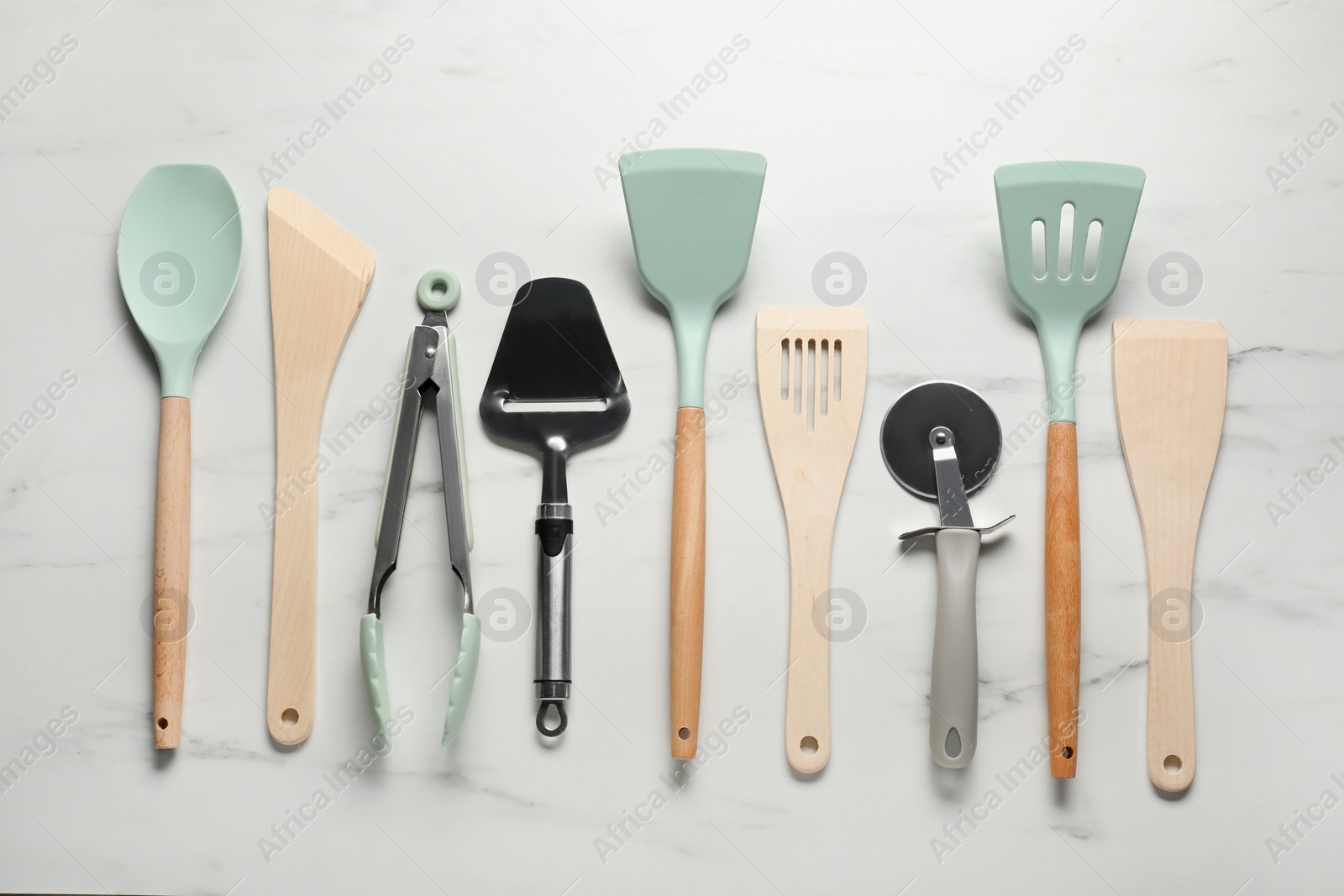 Photo of Different spatulas and other kitchen utensils on white marble table, flat lay