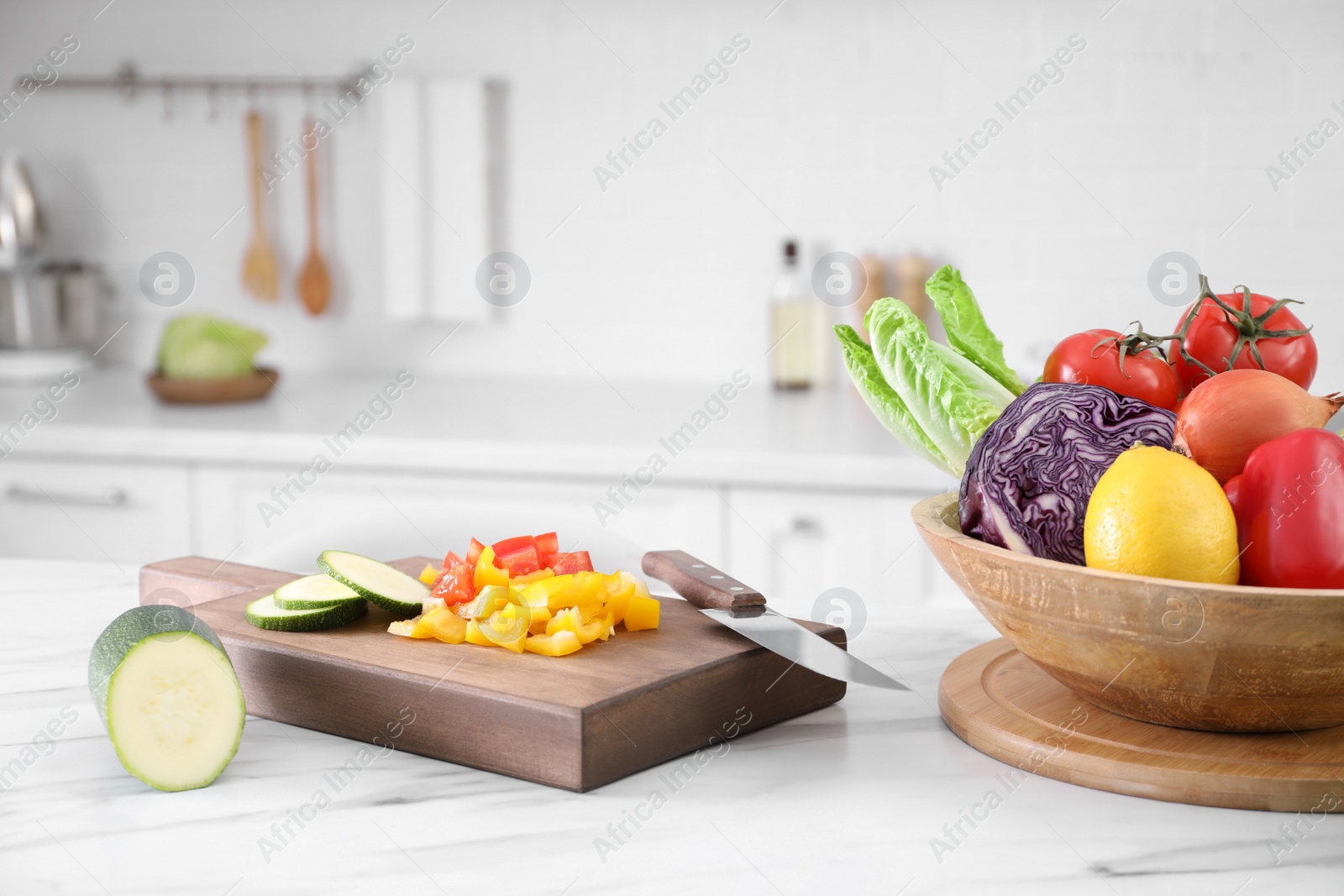 Photo of Different raw vegetables on white marble table in kitchen