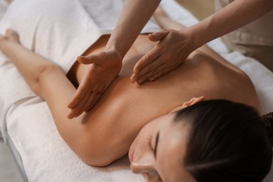 Photo of Woman receiving back massage on couch in spa salon