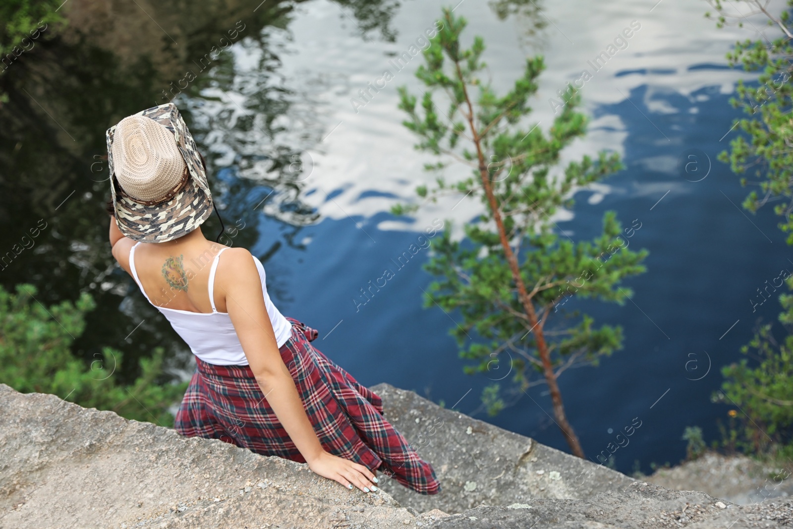 Photo of Young woman on rocky mountain near lake. Camping season