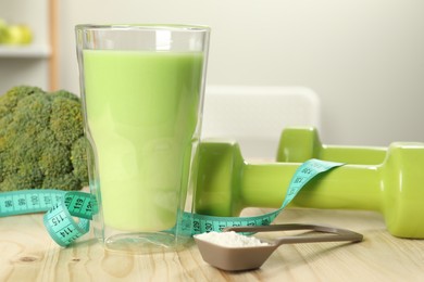 Photo of Tasty shake, dumbbells, measuring tape and powder on wooden table indoors, closeup. Weight loss