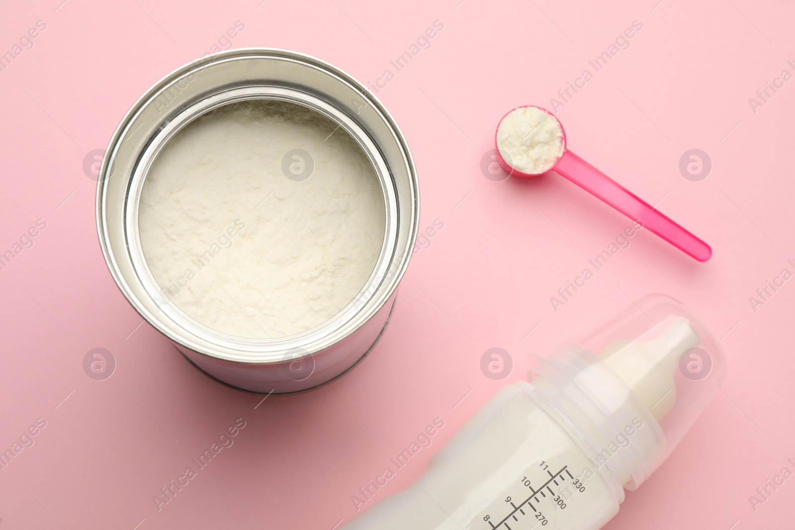 Photo of Feeding bottle with infant formula and powder on pink background, flat lay