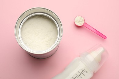 Photo of Feeding bottle with infant formula and powder on pink background, flat lay