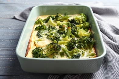 Photo of Tasty broccoli casserole in baking dish on wooden table