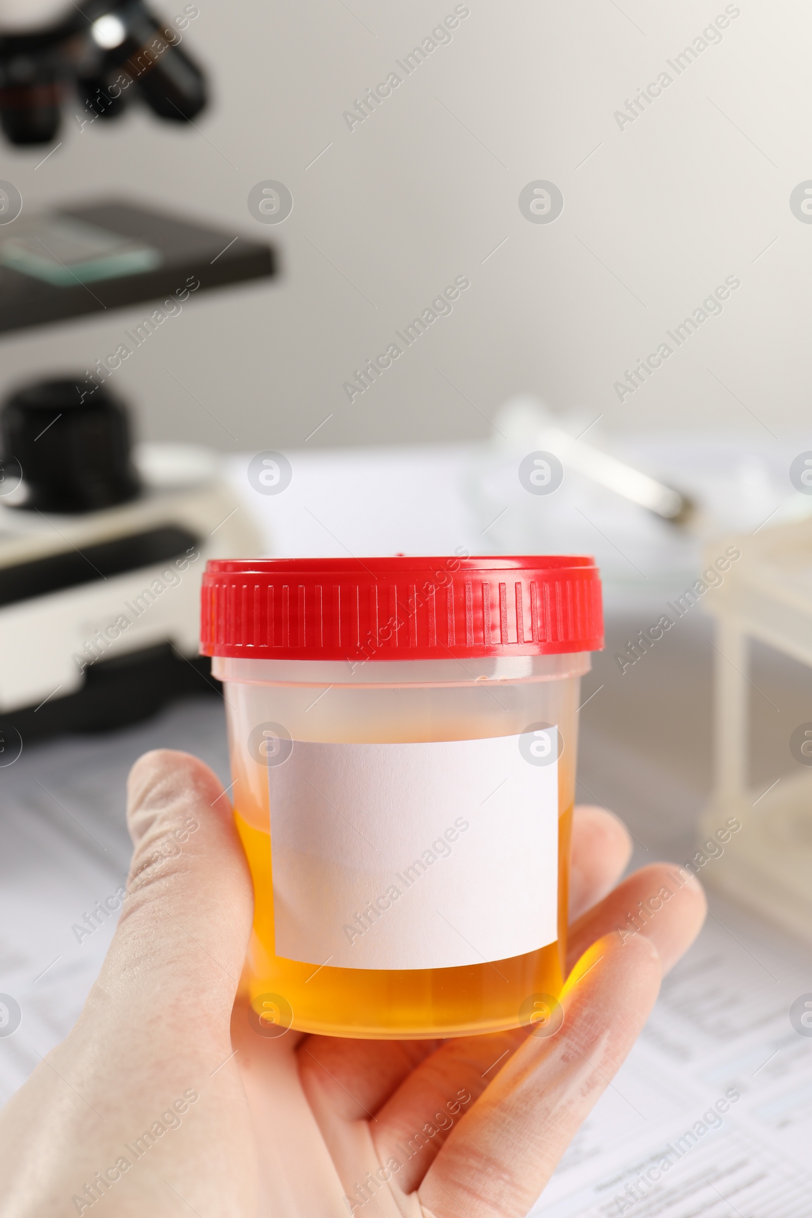 Photo of Nurse holding container with urine sample for analysis in laboratory, closeup