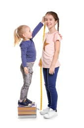 Little girls measuring their height on white background