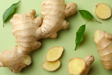 Photo of Fresh ginger with leaves on light pale green background, flat lay