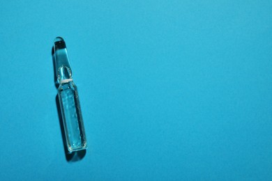 Pharmaceutical ampoule with medication on light blue background, top view. Space for text