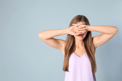 Young woman being blinded on grey background, space for text