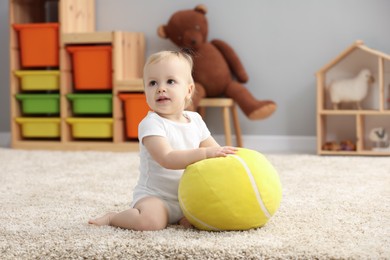 Children toys. Cute little boy playing with soft toy ball on rug at home