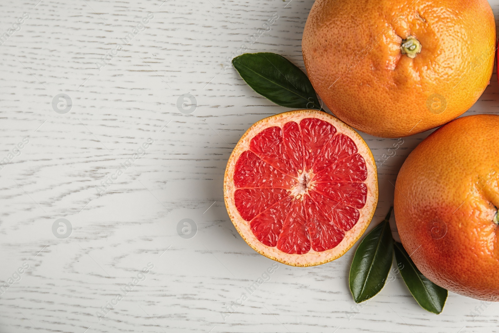 Photo of Fresh tasty grapefruits on white wooden background, top view with space for text