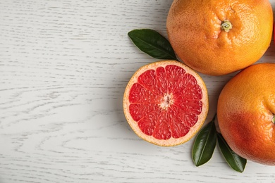 Fresh tasty grapefruits on white wooden background, top view with space for text