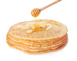 Photo of Sweet maple syrup dripping from dipper onto tasty thin pancakes on white background