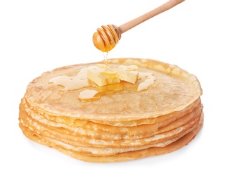 Sweet maple syrup dripping from dipper onto tasty thin pancakes on white background