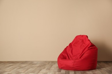 Photo of Red bean bag chair on floor near beige wall indoors, space for text