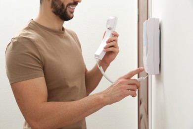 Man pressing button on intercom panel indoors, closeup