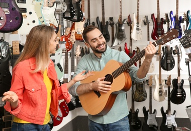 Photo of Young people choosing guitar in music store